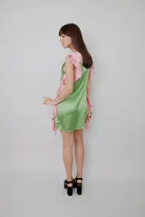 Vestido corto de satén verde con bordados pequeños y volados laterales de color rosado.