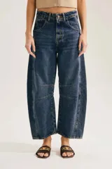 Jean barrel de tiro alto en denim azul con lavado desgastado, silueta curva y costuras decorativas a la altura de la rodilla.