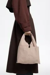 Bolso bandolera de estructura blanda marca Bimba y Lola, confeccionado en nylon con detalles en cuero. Presenta doble asa de mano, correa de tejido regulable y extraíble, cierre de cordón y logo metálico en el frente.