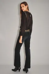 Pantalón de jean color negro, de corte recto y tiro alto, con acabado liso y costuras al tono.