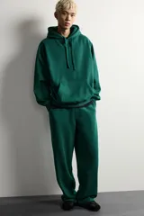 Pantalón jogger de corte relajado y pernera ancha, confeccionado en tejido de algodón con interior perchado. Cuenta con cintura elástica ajustable mediante cordón interior, bolsillos laterales y un bolsillo trasero de plastrón.