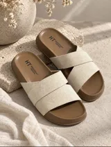 Sandalias planas con base marrón y tiras cruzadas en color beige de textura suave.