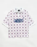 Camiseta tipo polo de estilo deportivo, con diseño a cuadros en tonos blanco y lila. Presenta cuello polo, mangas cortas y estampa gráfica circular en el frente con la inscripción 'anm'.