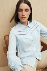 Camisa verde clara de manga larga confeccionada en viscosa ligera, con cuello clásico, cierre frontal con botones, detalles calados en la parte superior y pequeños volados.