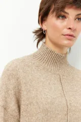 Polera de tejido de punto color beige, con cuello alto acanalado, manga larga y costura vertical decorativa en el frente.