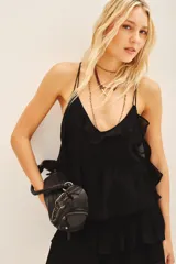 Top negro con escote en V, decorado con volados en el frente y breteles finos dobles. Confeccionado en viscosa georgette, presenta un ajuste elástico en la cintura y forrería a tono.