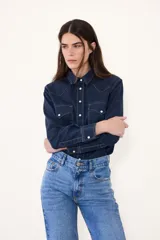Camisa de jean de corte western, color azul oscuro, con costuras en contraste, bolsillos frontales con solapa y cierre de botones a presión.