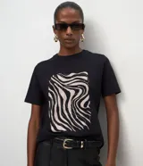 Remera de algodón color negro con cuello redondo y mangas cortas. Presenta una estampa frontal abstracta con líneas onduladas en tonos claros.