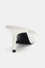 Sandalia de tacón fino color blanco, con tira delantera ancha con detalle de lazo y terminación en punta redonda.