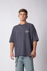 Remera oversize gris oscuro, confeccionada en algodón premium de alto gramaje. Presenta un estampado frontal sutil con un oso y el texto "Richer & Louder VCP".