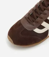 Championes estilo chutera marca Satinato, color marrón con detalles laterales en color crema. Presentan punta redondeada, cierre por cordones y suela plana de goma.