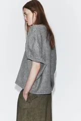 Jersey de punto liso con escote redondo y manga corta, de corte amplio y holgado.
