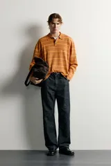 Polo de punto de algodón con diseño a rayas horizontales en tonos tostado y amarillo, cuello solapa y cierre frontal parcial con tres botones. Presenta mangas largas y efecto lavado.