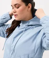 Campera rompevientos deportiva color celeste, con capucha y cordones de ajuste, cierre frontal completo, mangas largas con puños elásticos y bolsillos funcionales.