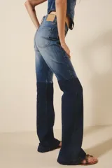 Pantalón de jean con tiro medio, corte ajustado hasta la rodilla y pierna acampanada. Presenta un diseño de tres tonos de azul logrado mediante procesos de lavado y recortes laterales a contratono.