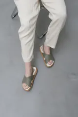 Sandalias bajas color verde oliva, con dos tiras anchas cruzadas sobre el empeine y tira trasera con hebilla.