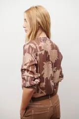 Camisa de manga larga con estampado floral en tonos marrones y negros, cuello mao y cierre frontal parcial con botones.