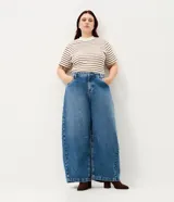 Pantalón de jean azul con lavado medio, corte barrel de piernas amplias, cintura con pasacintos, bolsillos funcionales y pinzas en las piernas.