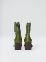 Botas de caña media color marrón, confeccionadas en cuero con acabado brillante. Presentan punta cuadrada, taco de madera y un distintivo bordado decorativo en color rojo que recorre el empeine hasta la punta.