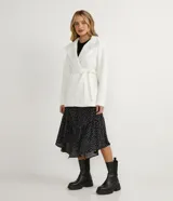 Campera alargada de polivelour color blanco, con cuello alto que se pliega y se ata a la cintura, mangas largas, abotonado frontal doble, bolsillos y cinturón.