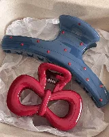 Set de dos clips para el pelo: uno azul con lunares rojos y otro rojo con forma de moño.
