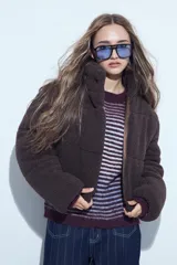 Campera puffer de corderito negro con cuello alto y diseño oversized. Presenta una textura tipo teddy, cierre frontal y corte a la cintura.