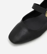 Zapatilla tipo bailarina Satinato de cuero negro, con punta cuadrada, tacón bajo y tira en el empeine con hebilla metálica dorada grande.