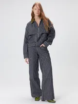 Campera de denim a rayas verticales con cuello de pana en color bordó. Presenta cierre frontal, mangas desmontables con cierre en los hombros, canesú en el pecho y bolsillos de parche cuadrados.