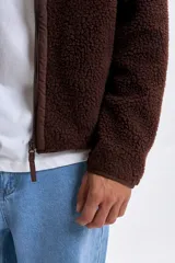 Campera de sherpa color marrón con cierre frontal completo, cuello alto y bolsillo en el pecho con cierre.