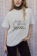 Remera de algodón color beige con estampa frontal que incluye la frase 'Jardín de Invierno' y un diseño gráfico de un animal con patrón de cuadros.