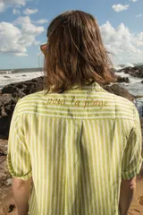 Camisa de manga corta oversize en lino rayado, con cuello camisero, cierre frontal con botones y bordado playero en el frente.