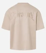 Remera oversized color beige confeccionada en gamuza sintética. Presenta cuello redondo, mangas cortas y bordado de cruz en el frente.