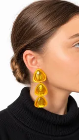 Aros colgantes de resina en tonos amarillo y dorado, compuestos por tres piezas triangulares apiladas en cascada con acabado brillante.