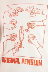 Remera de cuello redondo y manga corta color beige, con estampado gráfico frontal en color naranja que representa un brindis con diversas copas y el logo de la marca Original Penguin.