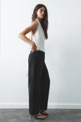 Top blanco de tejido satinado con cuello halter drapeado ajustable con lazada en el cuello y espalda descubierta con lazada.