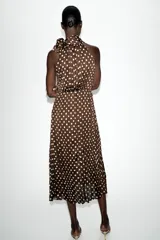 Vestido midi de color marrón con estampado de lunares blancos, cuello halter con lazo y diseño plisado.