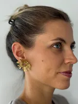 Aros colgantes dorados con forma de sol, formados por canutillos metálicos.