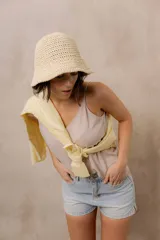 Gorro tipo bucket tejido a crochet de trama abierta, color natural, con ala corta y flexible.