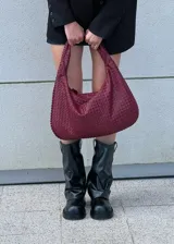 Cartera de hombro color bordó con diseño tejido.