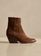 Bota corta de estilo western confeccionada en cuero vacuno color marrón, con taco cuadrado de 7 cm y puntera metálica decorativa.