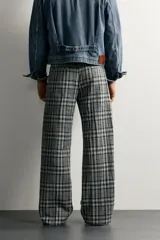 Pantalón flare fit confeccionado en tejido con algodón, con estampado a cuadros en tonos grises y negros. Cuenta con bolsillos laterales, bolsillos traseros de vivo y cierre frontal con cremallera y botón.