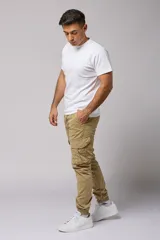 Pantalón cargo color beige de gabardina, con corte ajustado, bolsillos laterales con fuelle y puños elásticos en los tobillos.