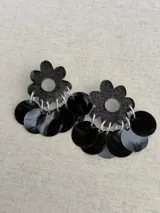 Aros dorados con forma de flor brillante en la parte superior y múltiples discos metálicos colgantes.