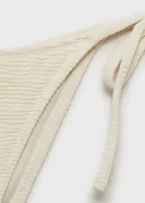 Braga de bikini blanca con textura, corte cheeky, forro interior y cierre de lazos laterales.