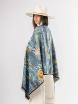 Pashmina de diseño artístico con estampado abstracto en tonos azules, celestes y amarillos. Presenta bordes con ribete oscuro y terminaciones con flecos cortos.