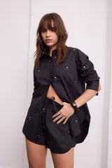 Short negro de algodón con bordados de pequeñas flores rosas y verdes, cuenta con cintura elástica y cordón ajustable.