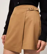 Short pollera de sastrería color marrón, confeccionado en mezcla de poliéster y viscosa, con diseño cruzado tipo envolvente.