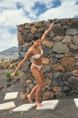 Conjunto de bikini color off white confeccionado en lycra texturada. Corpiño strapless con unión central mediante avío metálico y bombacha tipo vedetina.