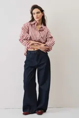Camisa a rayas verticales en tonos rosado y marrón, de manga larga abullonada, cuello camisero y cierre frontal de botones con pequeños apliques brillantes.