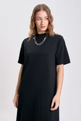 Vestido largo negro de manga corta, con cuello alto tipo mock neck y corte recto y holgado.